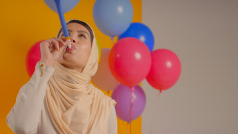Studioporträt-Einer-Frau-Im-Hijab,-Die-Ihren-Geburtstag-Mit-Luftballons-Und-Partygebläse-Feiert-1